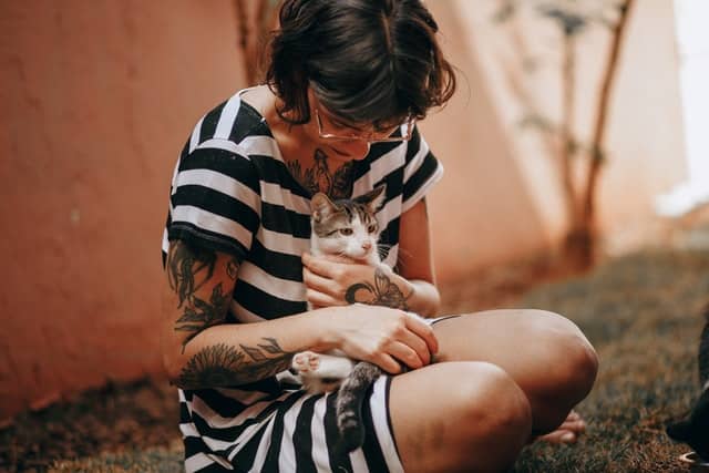 A woman plays with her cat with no adverse effects after it's been administered the HypoCat cat allergy vaccine