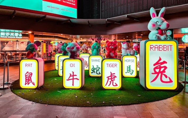 An indoor display of illuminated zodiac animal signs celebrates the Chinese New Year, featuring a grassy area adorned with radiant figures of the rat, ox, snake, tiger, horse, and rabbit.