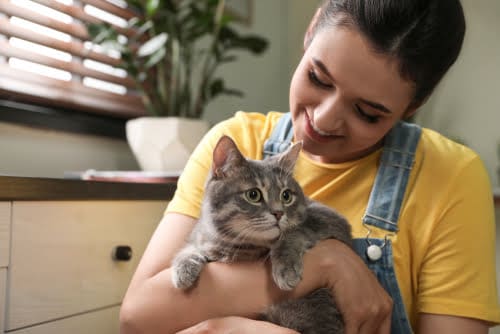 young woman holding and talking to cat