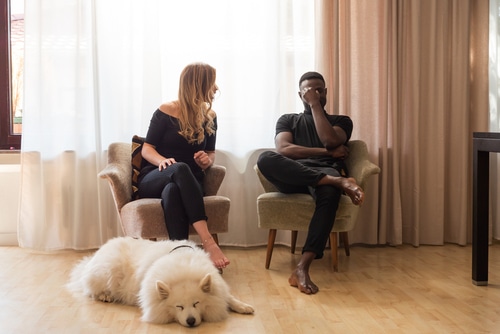 man and woman arguing with dog lying between them. Breakups are hard on pets
