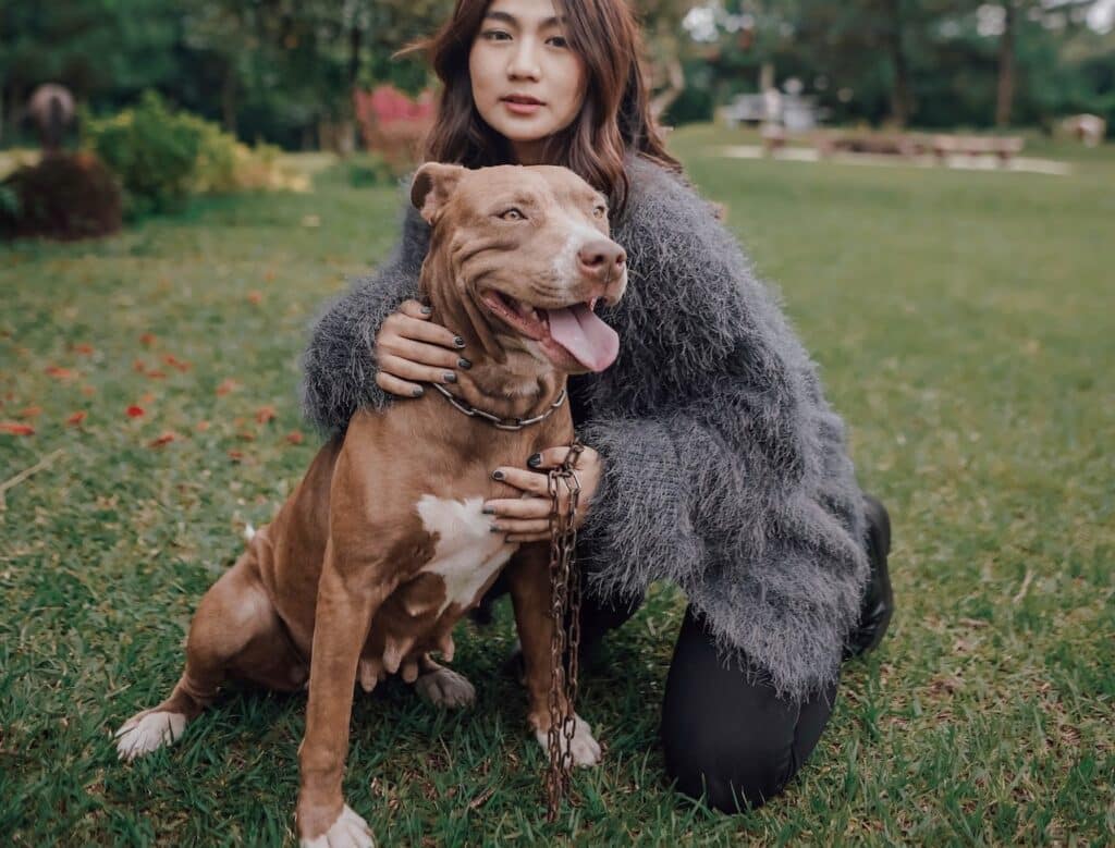 A woman posing with her dog in the grass during the Easter holidays.