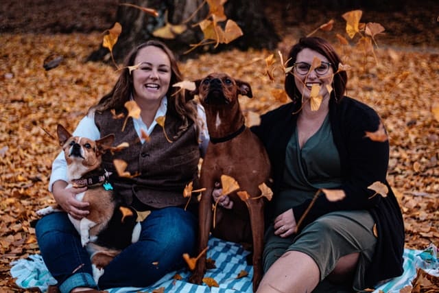 two Kiwi women and their pups in Autumn leaves