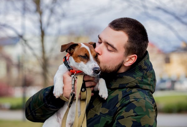 Young man with his dog, Jack Russell Terrier, on the city street in spring time.