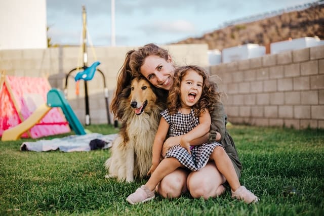 woman hugs her dog and her daughter and feels happy both the family and dog have dental insurance plans to guard them financially