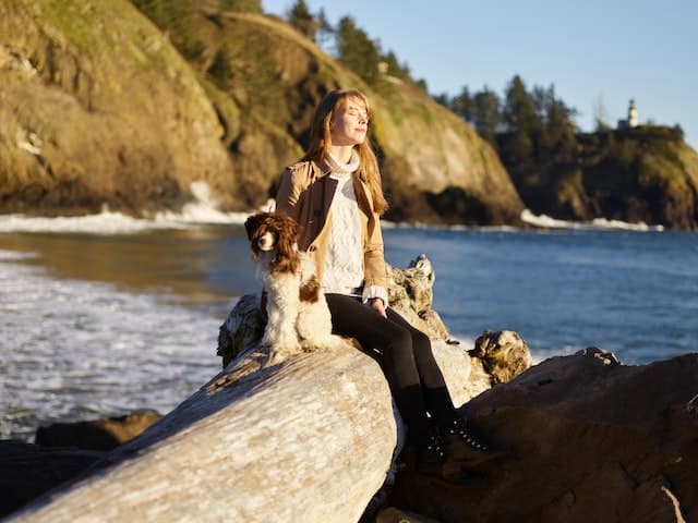 A woman sits with her pets on a boulder looking out at the sea and hopes that the lymphoma in her dog will be able to be treated and managed