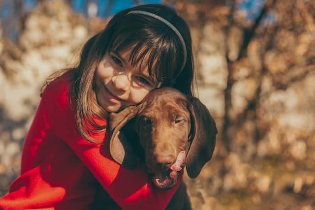 a little girl hugs her dog that has had dog insurance since it was a puppy