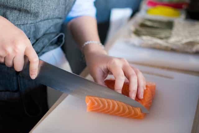A woman prepares raw fish salmon and wonders what human food is good for dogs and whether fish is one of these.