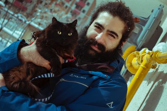 A man holds his kitty up to the camera for a snapshot on a cold wintery day