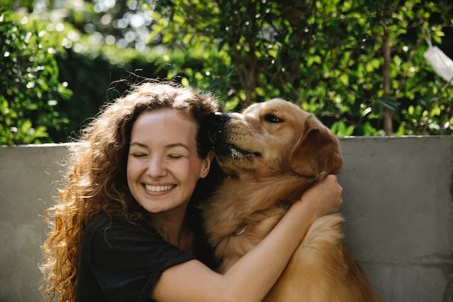 A woman embracing her golden retriever, celebrating his recovery after vet treatment and a speedy pet insurance claims process with PD Insurance