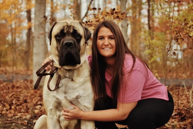 A woman posing with a large dog in the woods, with pet insurance claims being her top priority.