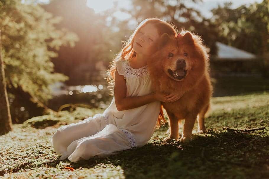 A girl is sitting on the ground with a dog named Spot.