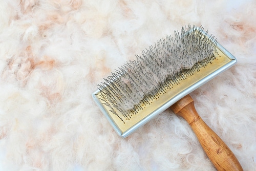 A dog brush on top of a pile of fur.