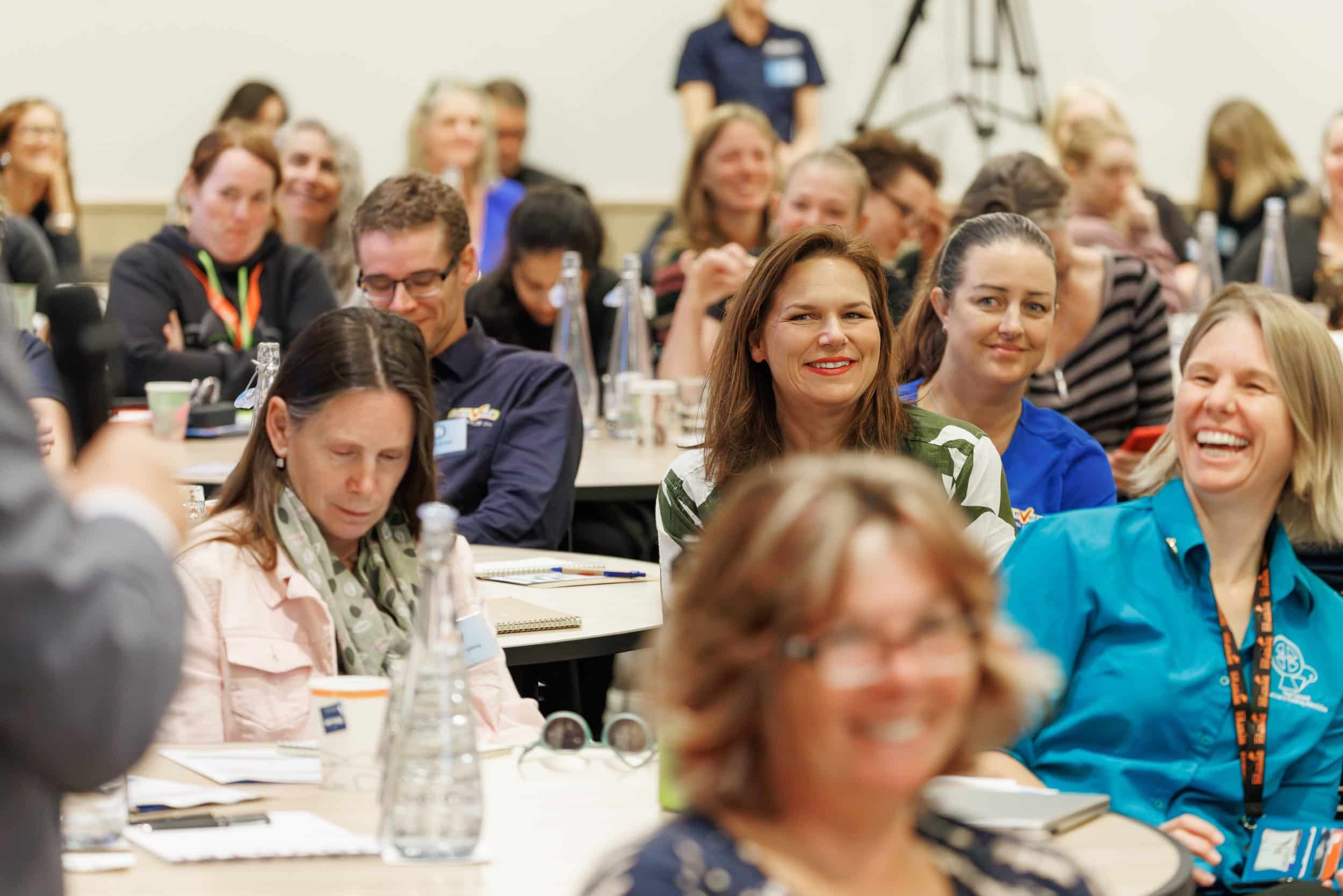 Audience members smiling and paying attention at the CANZ conference event.