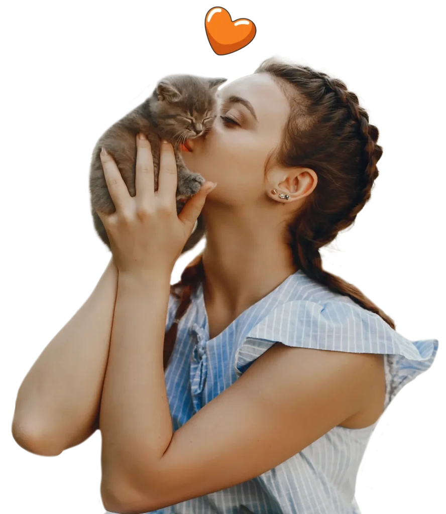A woman in a blue striped top kisses a small gray kitten while holding it up, with an orange heart above them—capturing the perfect moment to consider kitten insurance NZ for your furry friend's wellbeing.